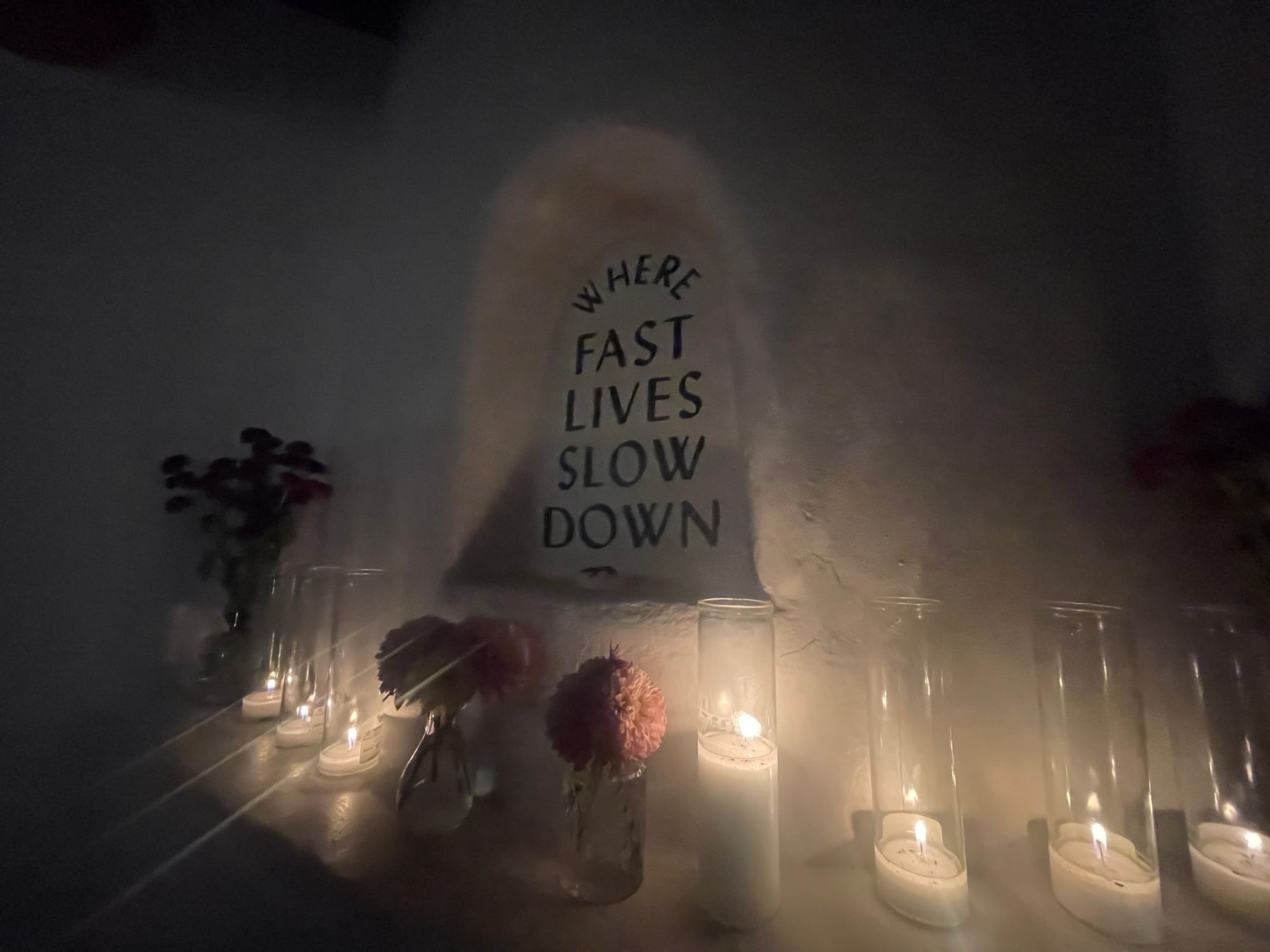 Candles lined up beneath a sign saying "Where fast lives slow down."