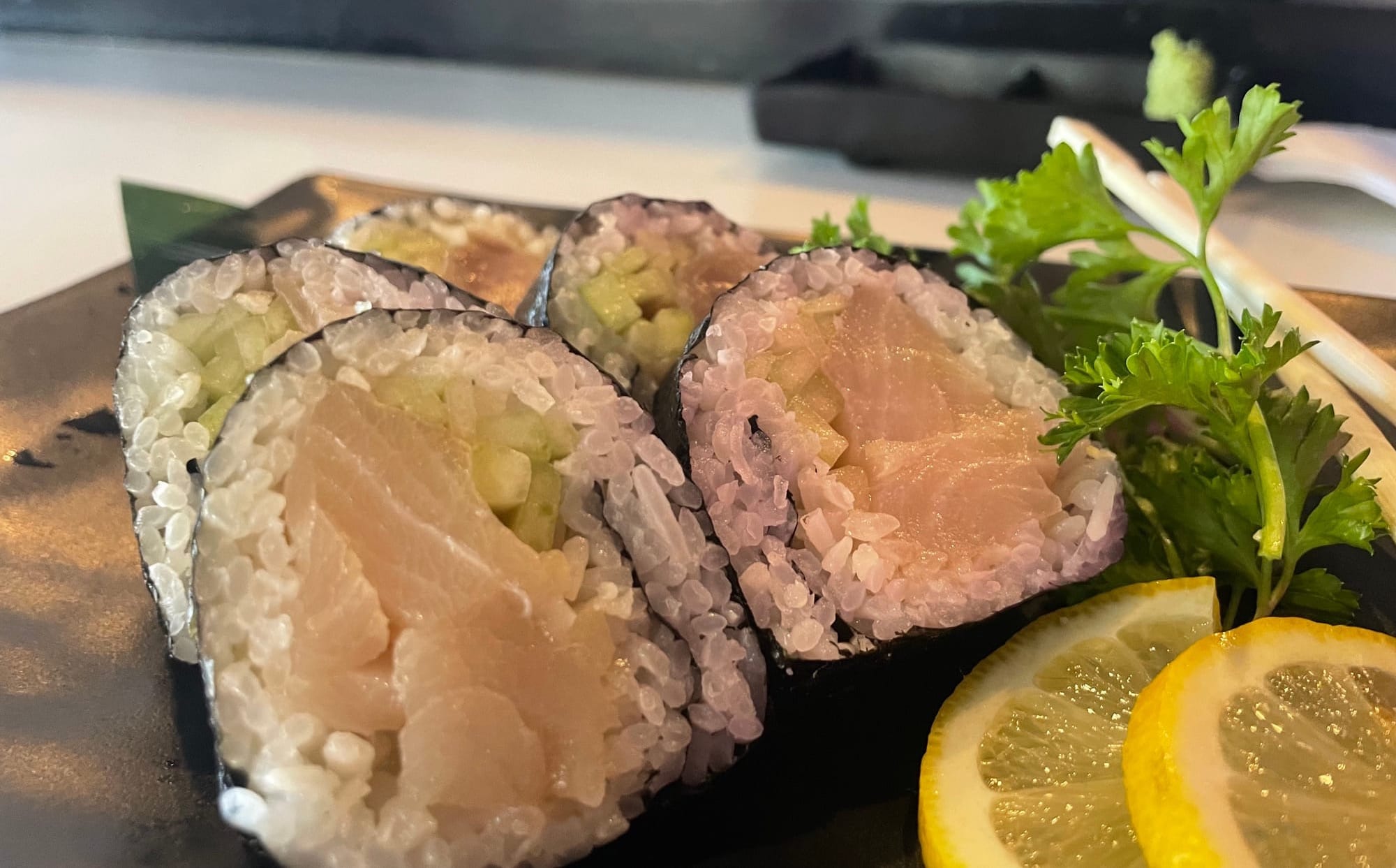 Albacore roll sushi next to sliced lemons and a parsley sprig.