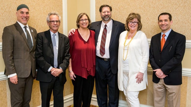 Six people — four men and two women — in business attire pose for a photo.