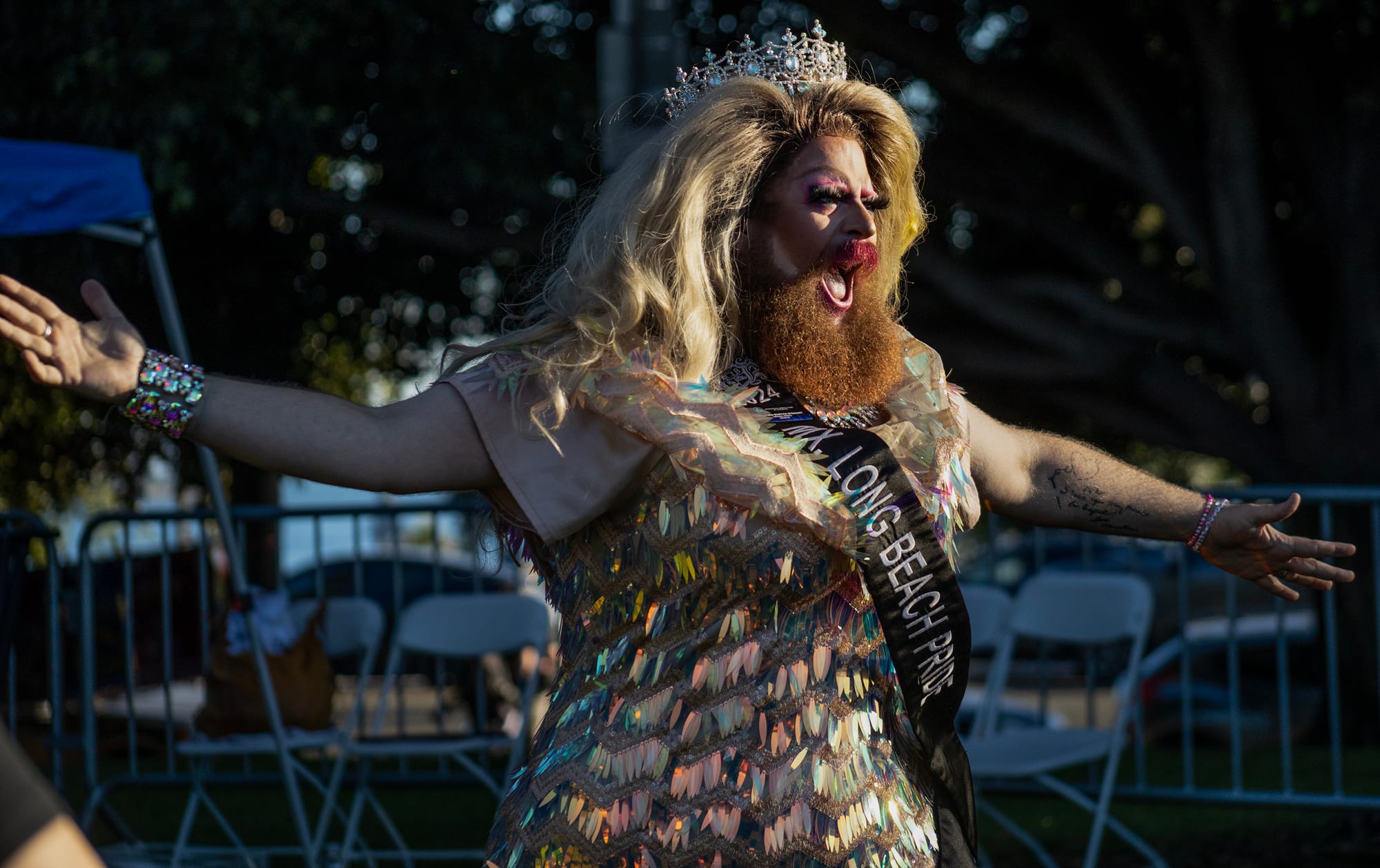 A bearded drag queen wearing a crown lip syncs.