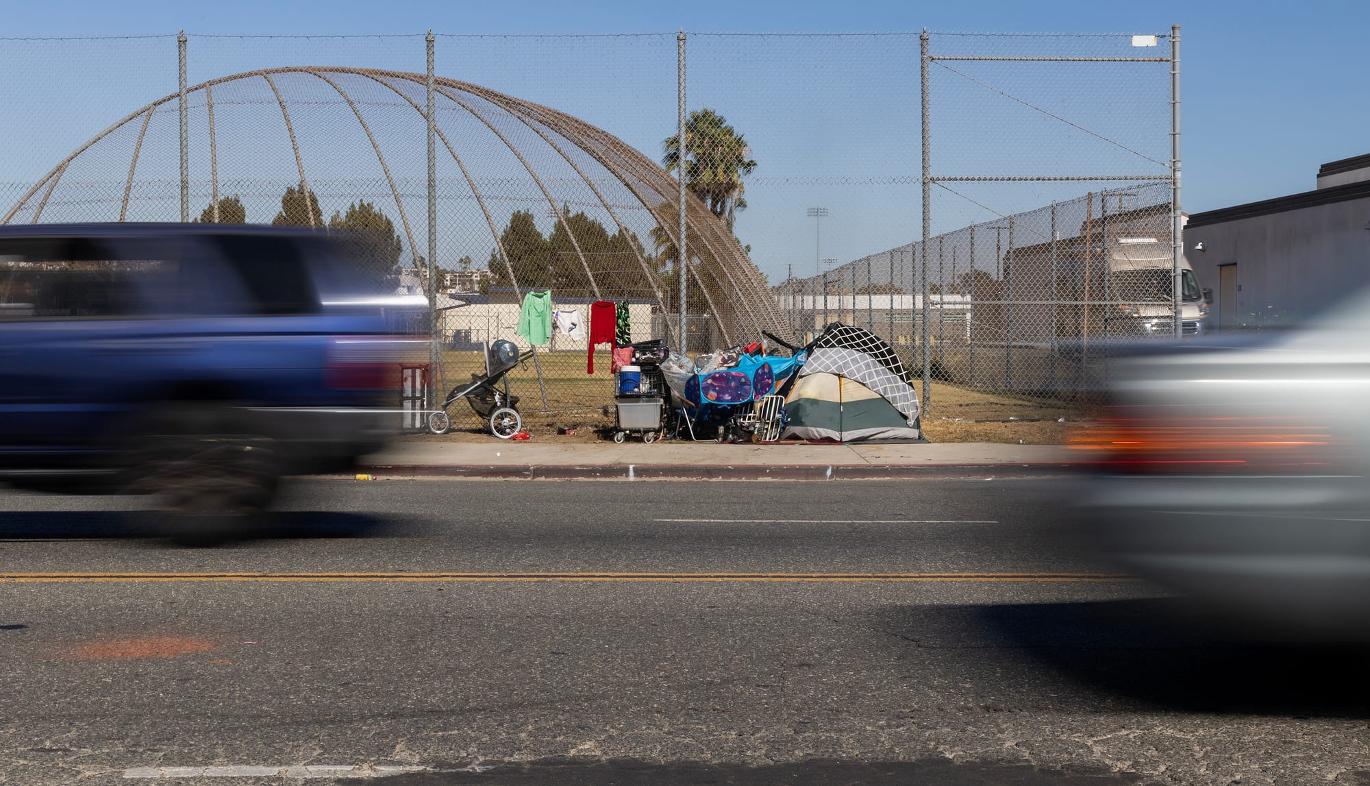 Cars are a blur as they drive by a tent on the side of the road.