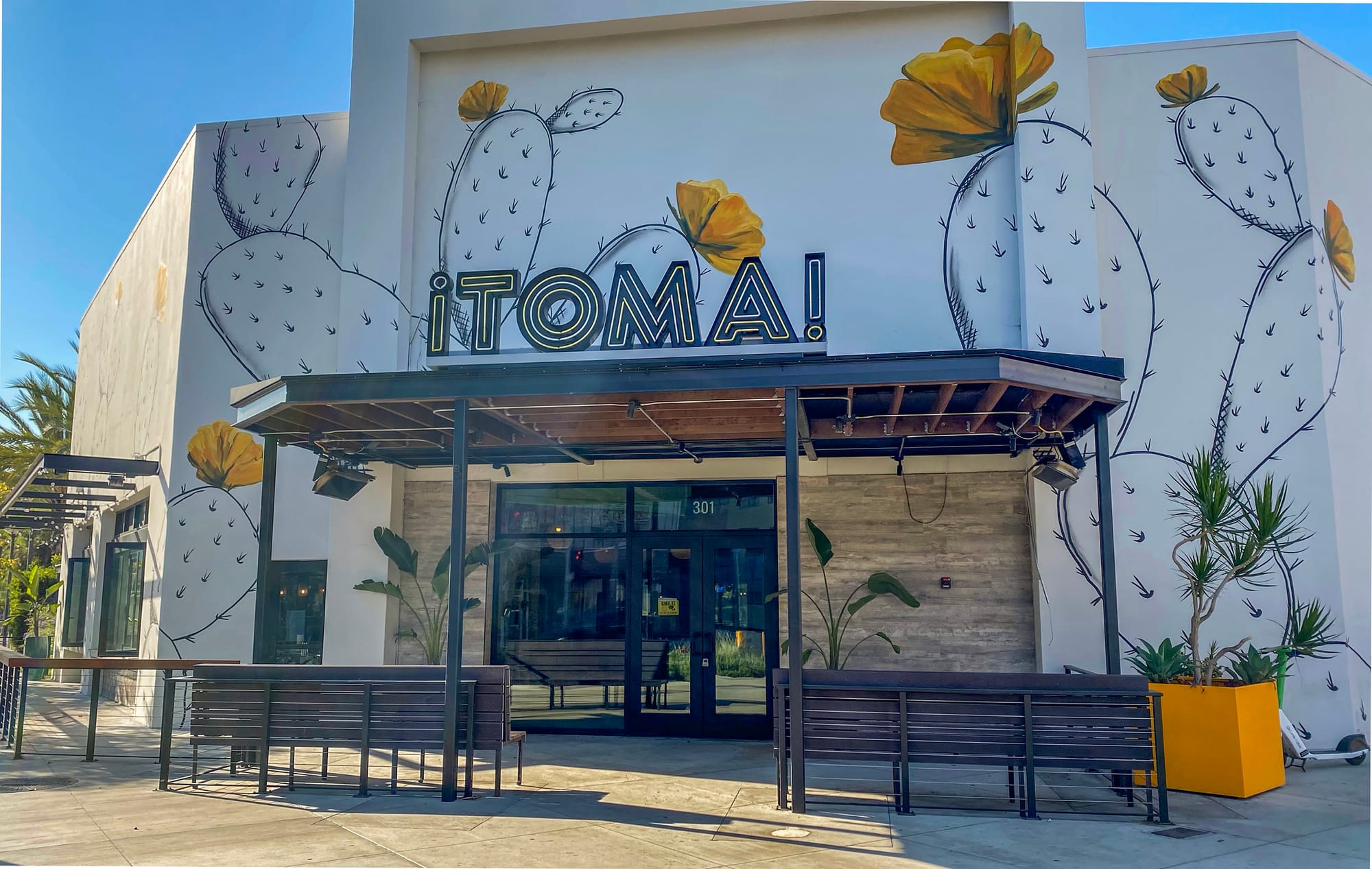 The front of a building with the name "Toma" and images of cacti on it.