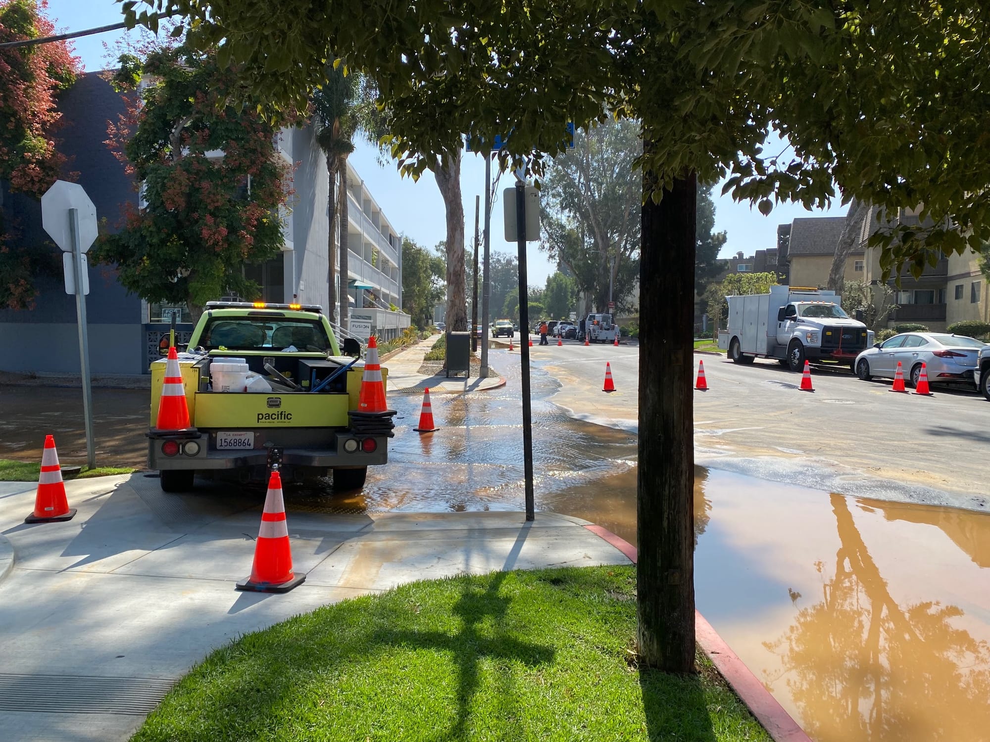 A yellow truck is blocking an intersection flooded with brown water.