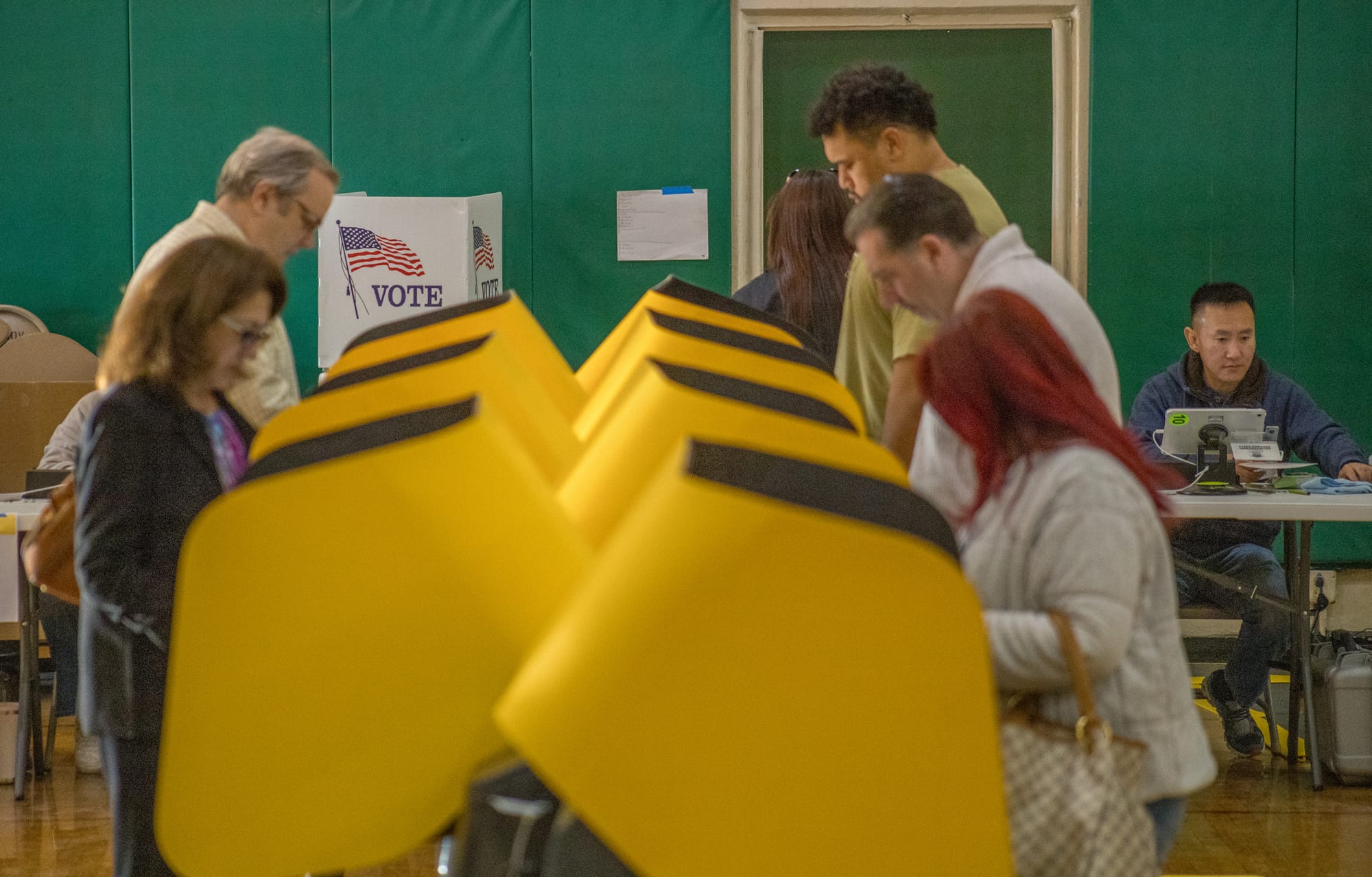 People stand at voting booths inside a park gymnasium.