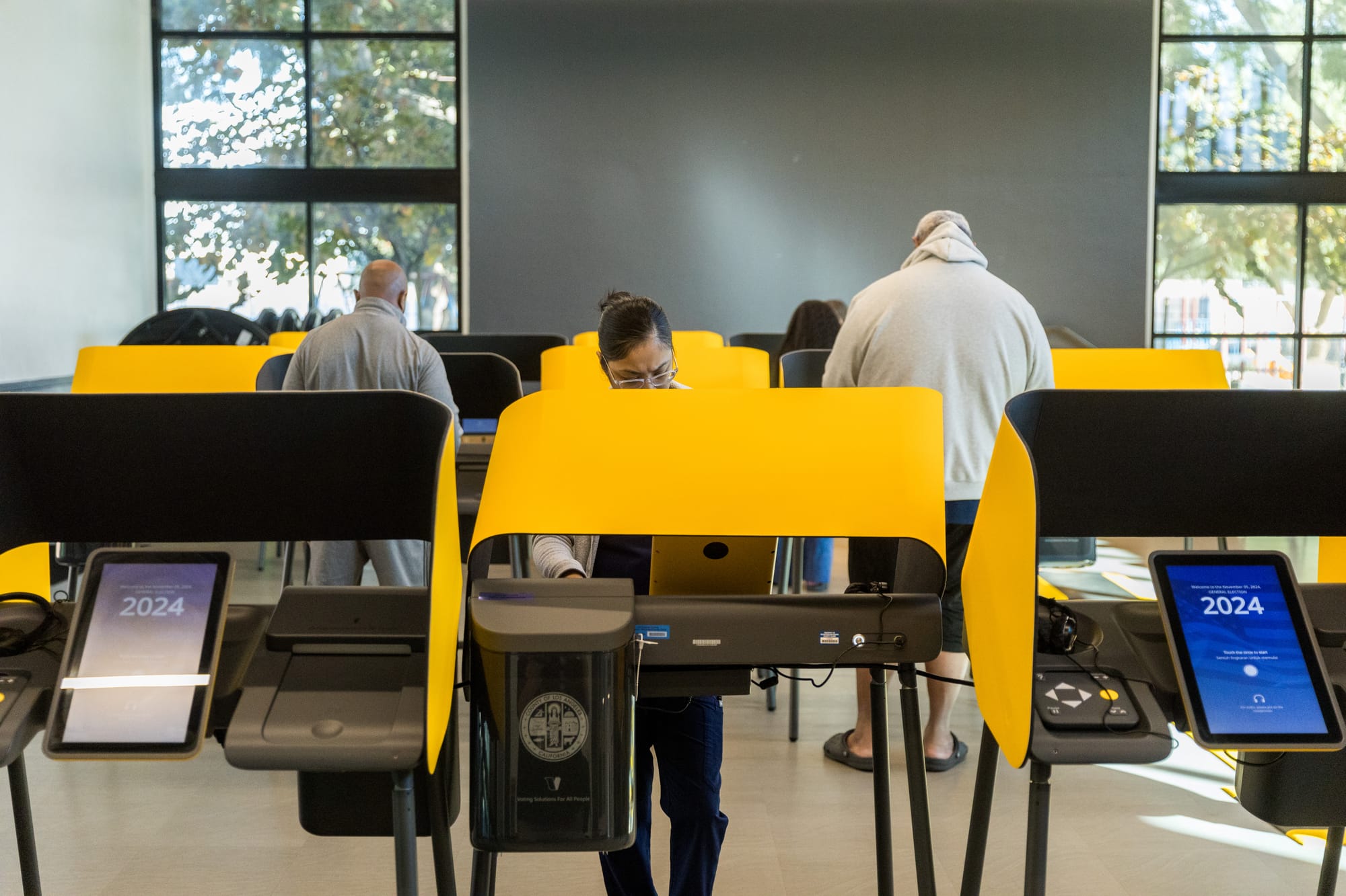 People stand at voting booths inside a park community center.