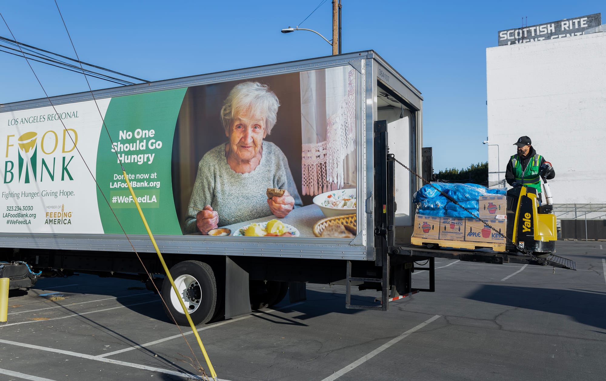 A man moves a pallet of food out of a large truck.