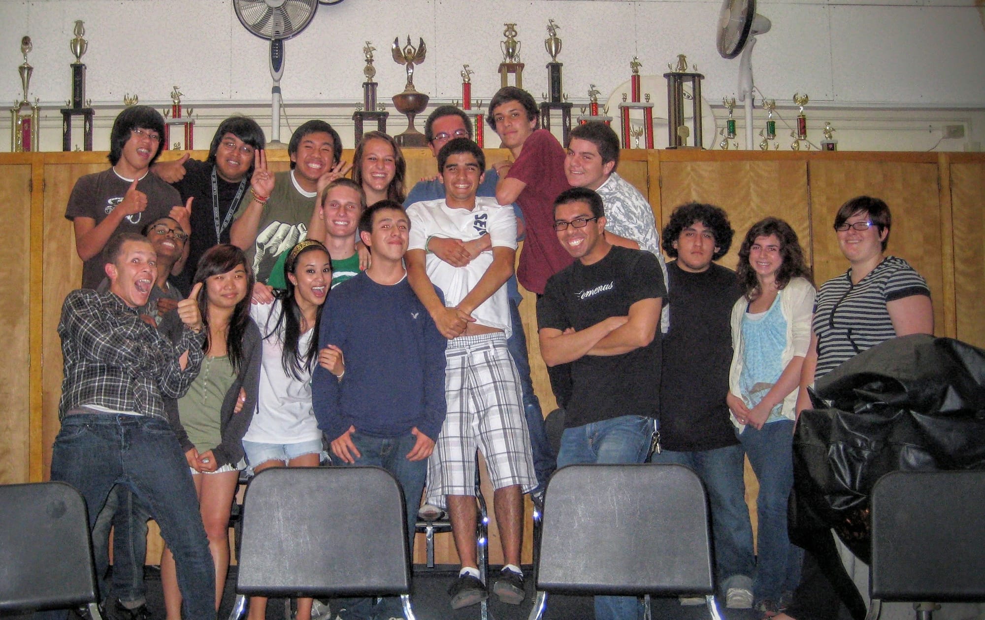 A large group of students pose for a photo with their coach inside a classroom.