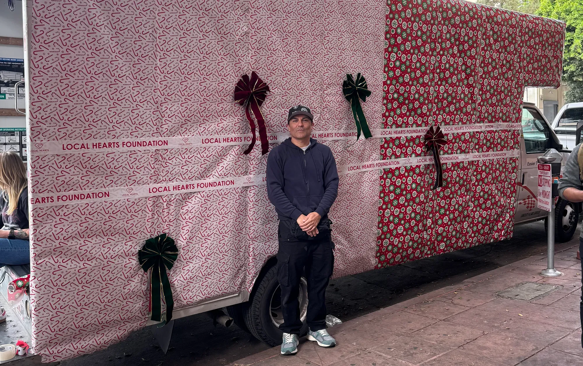 A man stands beside a truck decorated with Christmas wrapping paper.