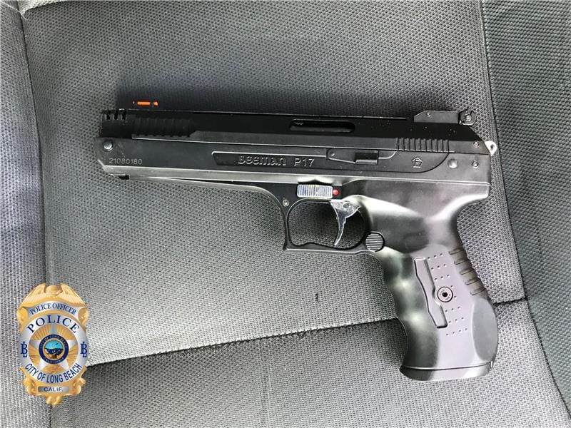 A black handgun resting on a dark gray fabric surface.