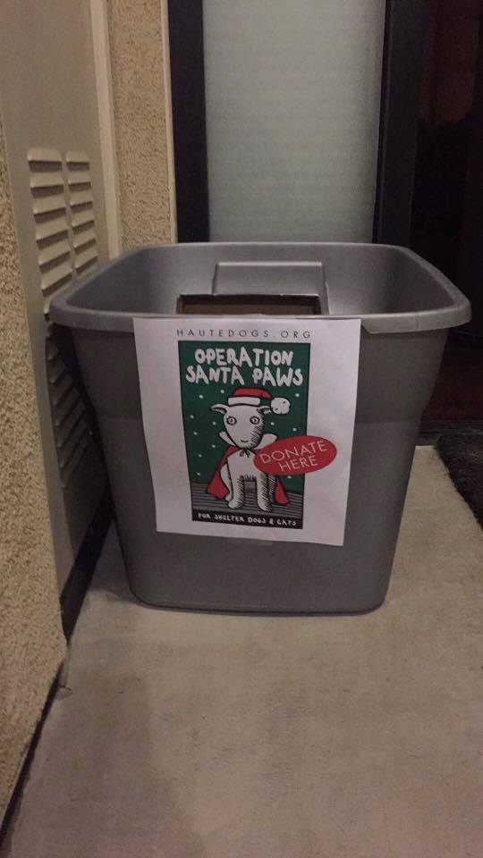 A gray bin with a sign saying "Operation Santa Paws" and showing a white dog in a red Santa hat and red cape.