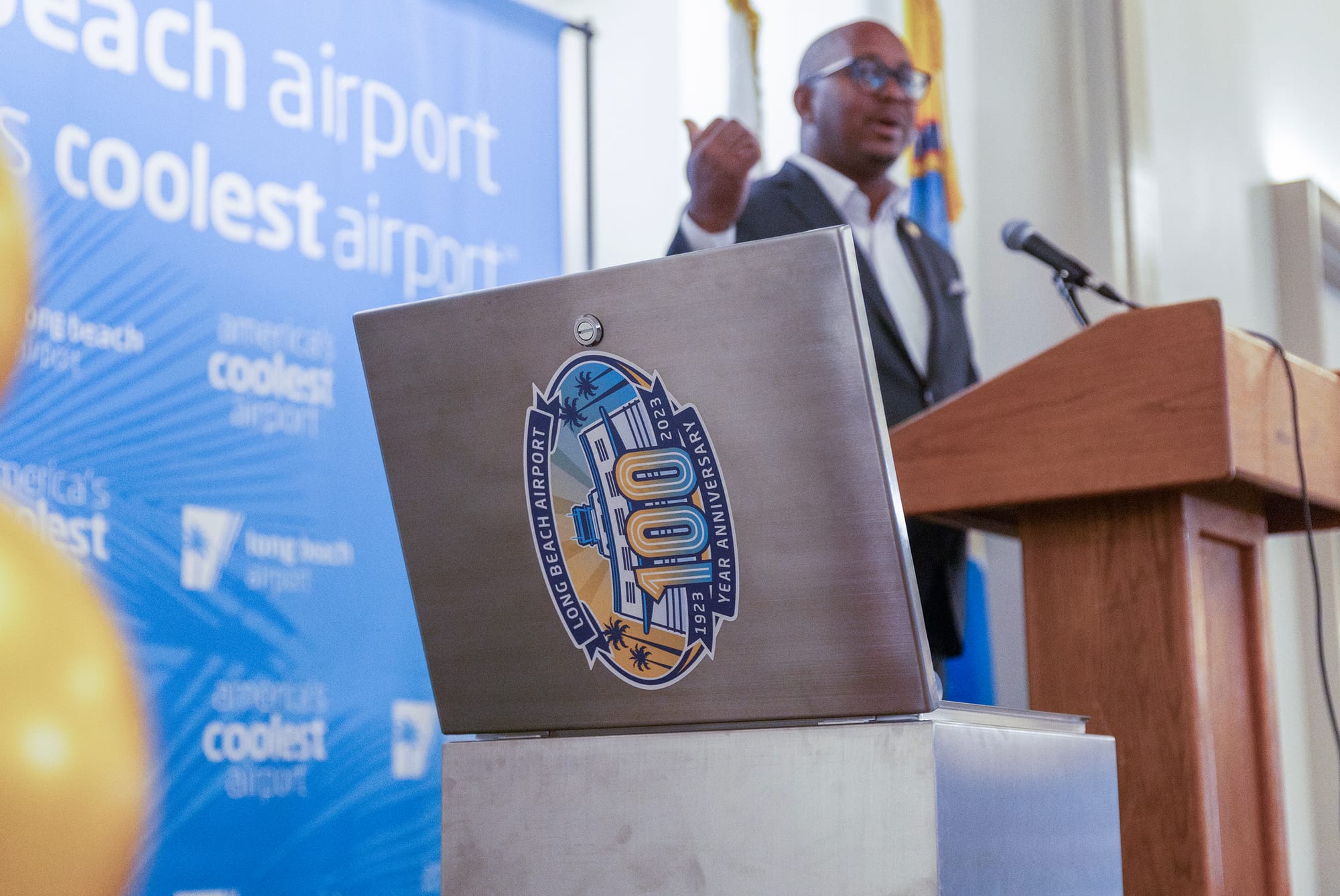 A silver metal time capsule is marked with a colorful logo for the Long Beach Airport 100th anniversary.