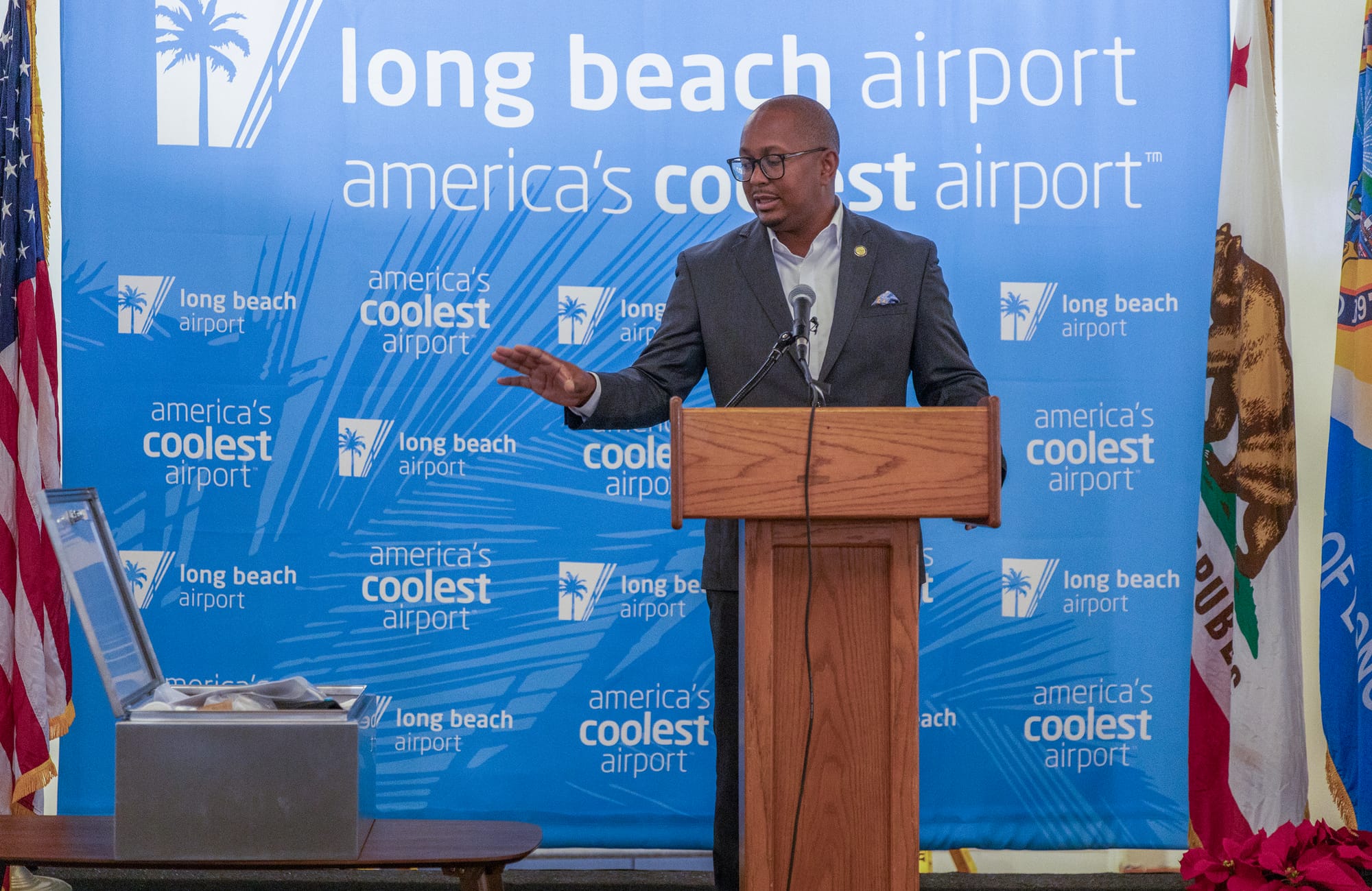 A man in a gray suit speaks at a podium.