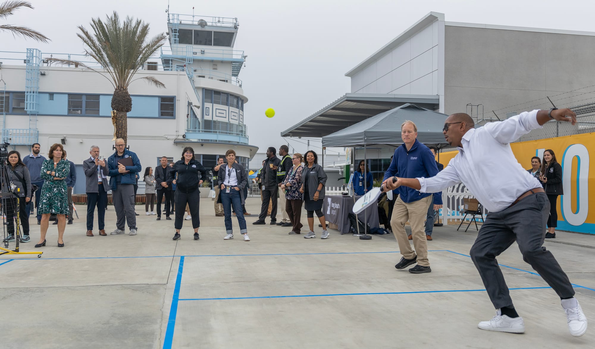 A crowd watches two men play a game wearing business casual clothes.