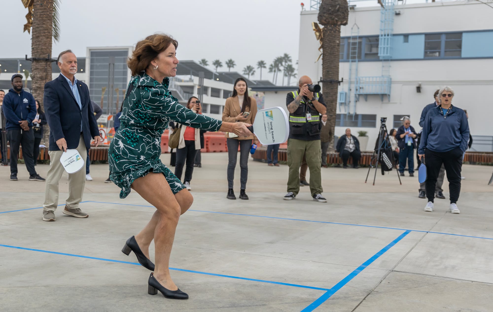 A woman plays a sport game in a green dress and black heels.