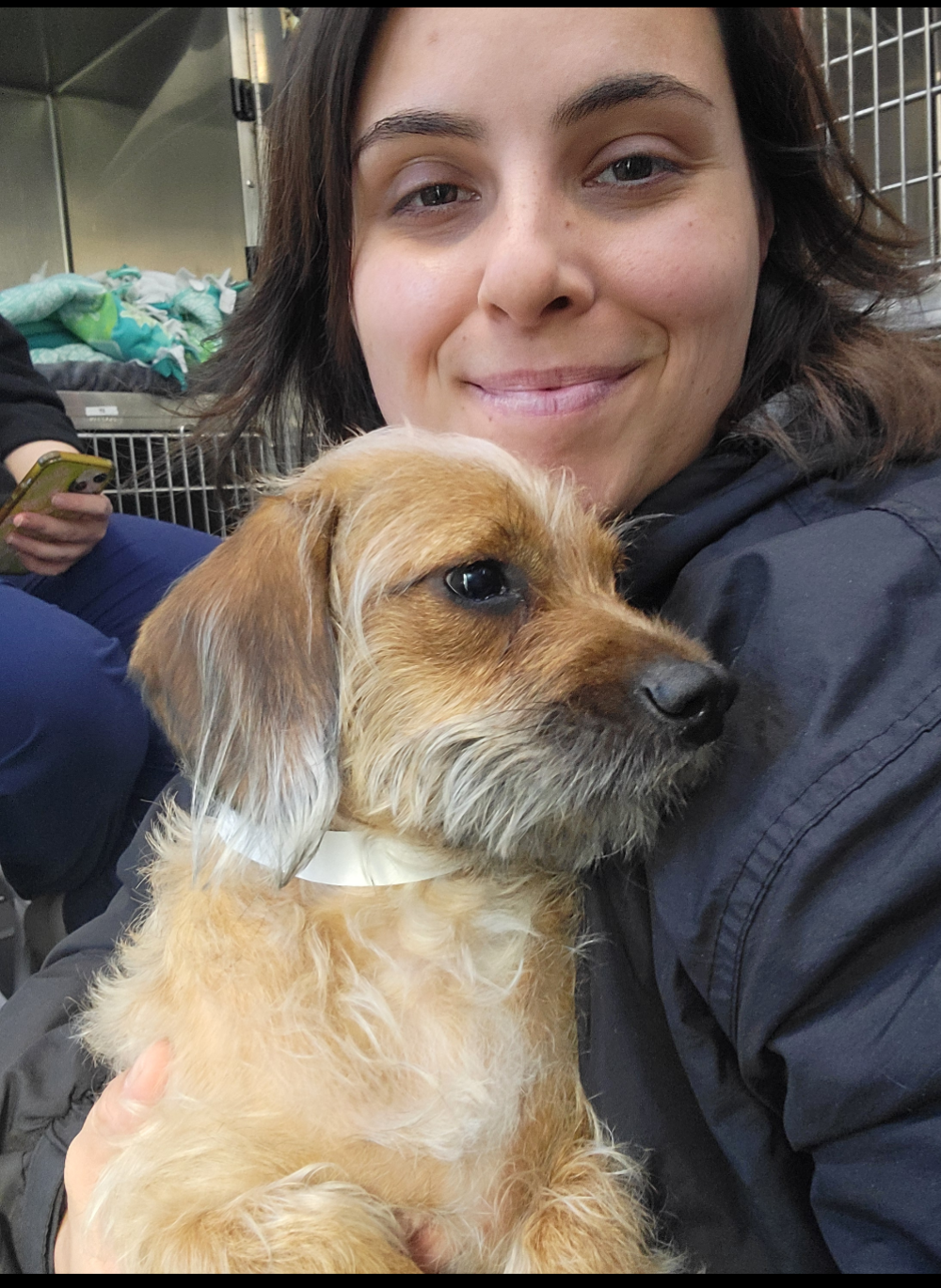 A woman holds a sweet light brown dog close.