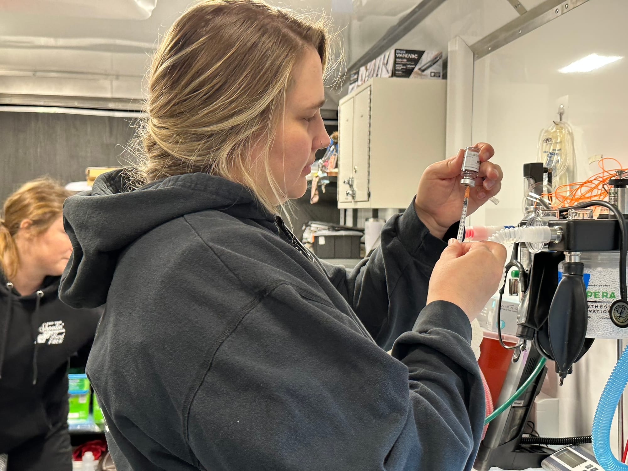 A woman in a gray hoodie readies a syringe.