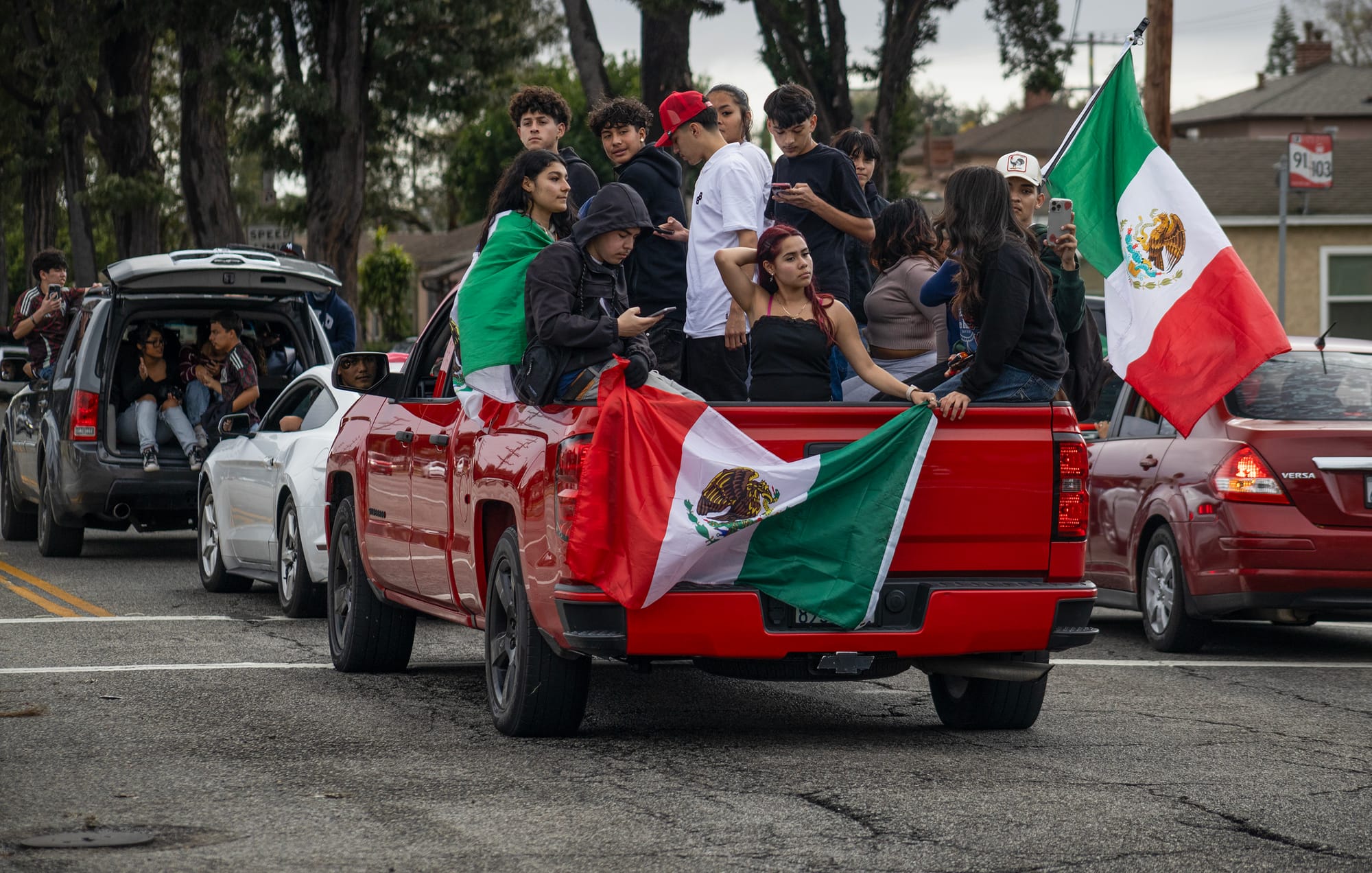 A group of young people sit in the back of a red truck.