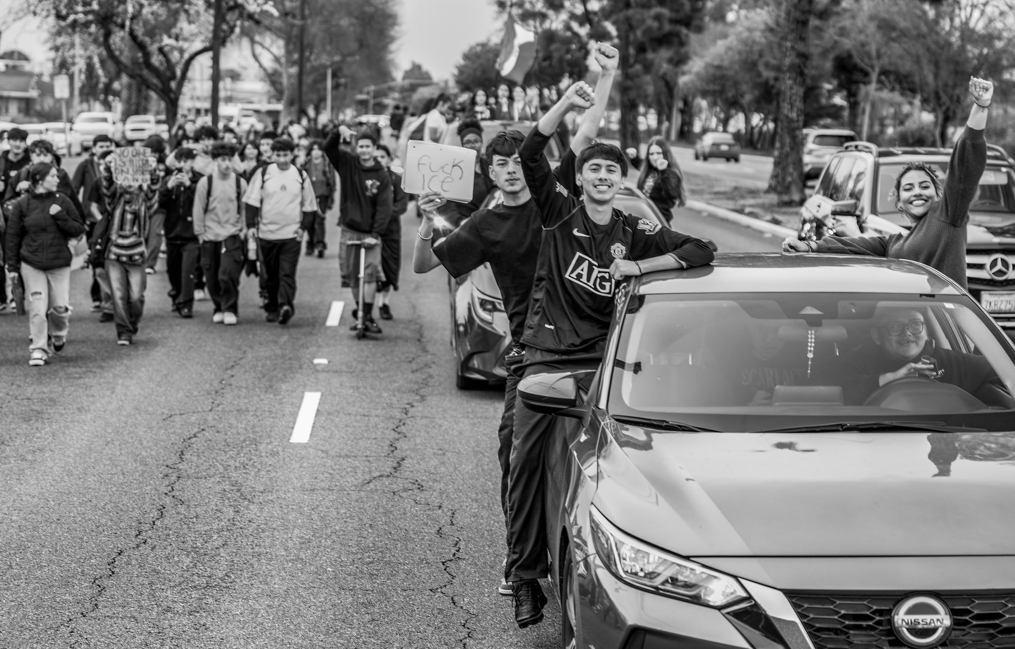 Black and white photo of people walking the street next to cars.