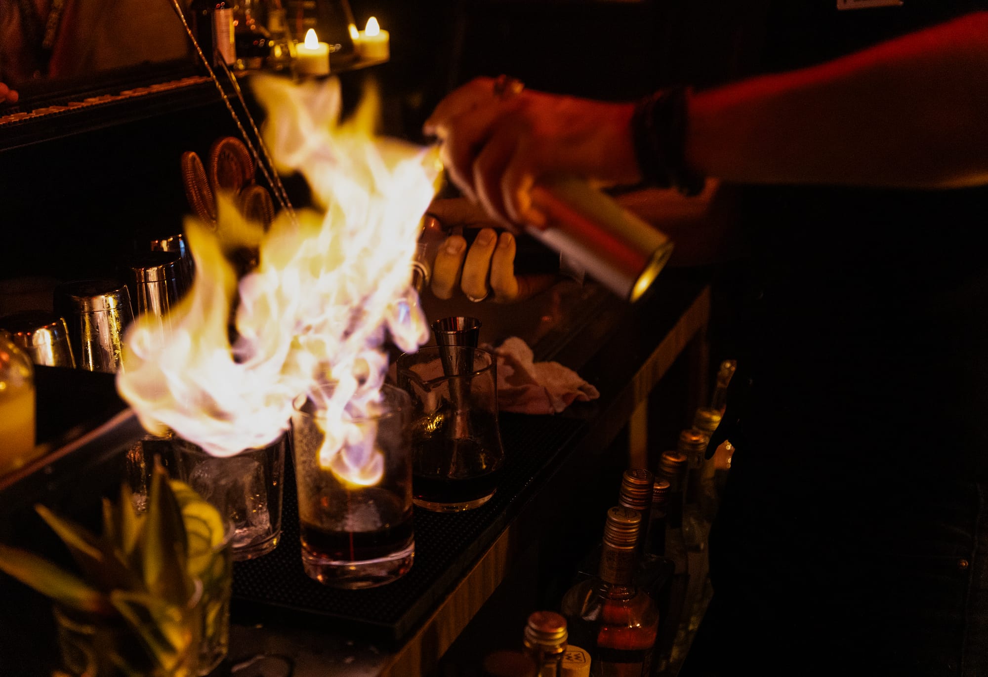 A person sprays fire into a glass.