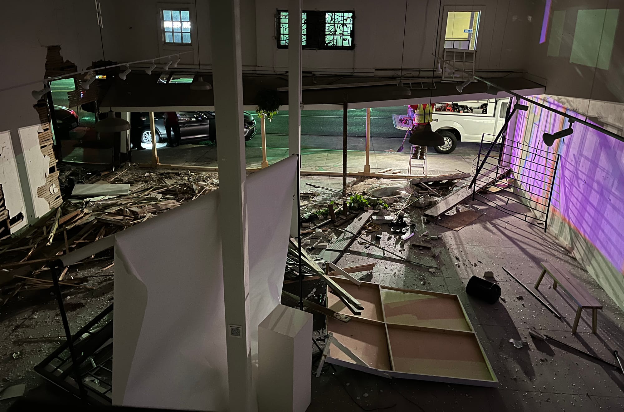 Debris litters the ground at the scene after a car crashed through a building.