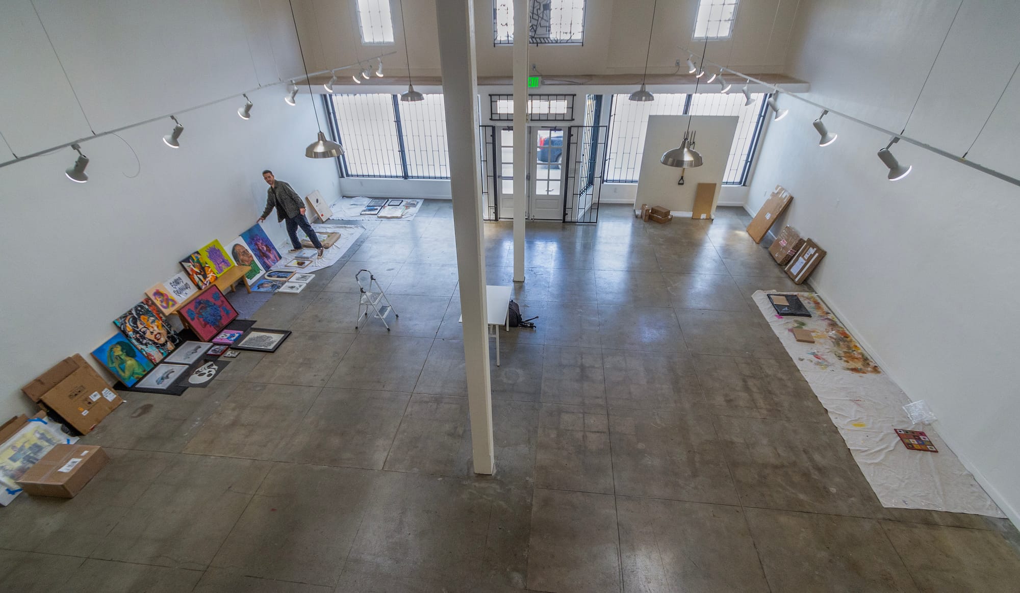 A man moves art in a large, white room.