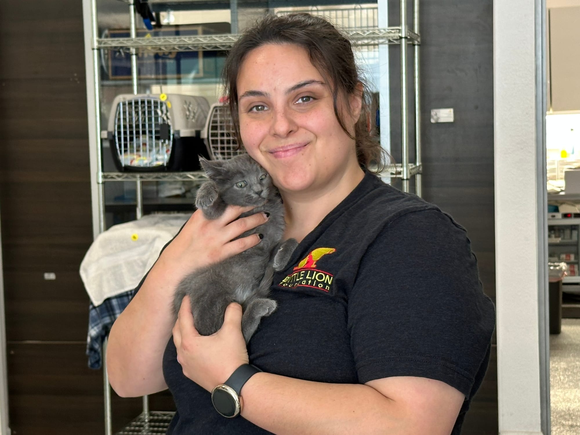 A woman cradles a gray kitten.