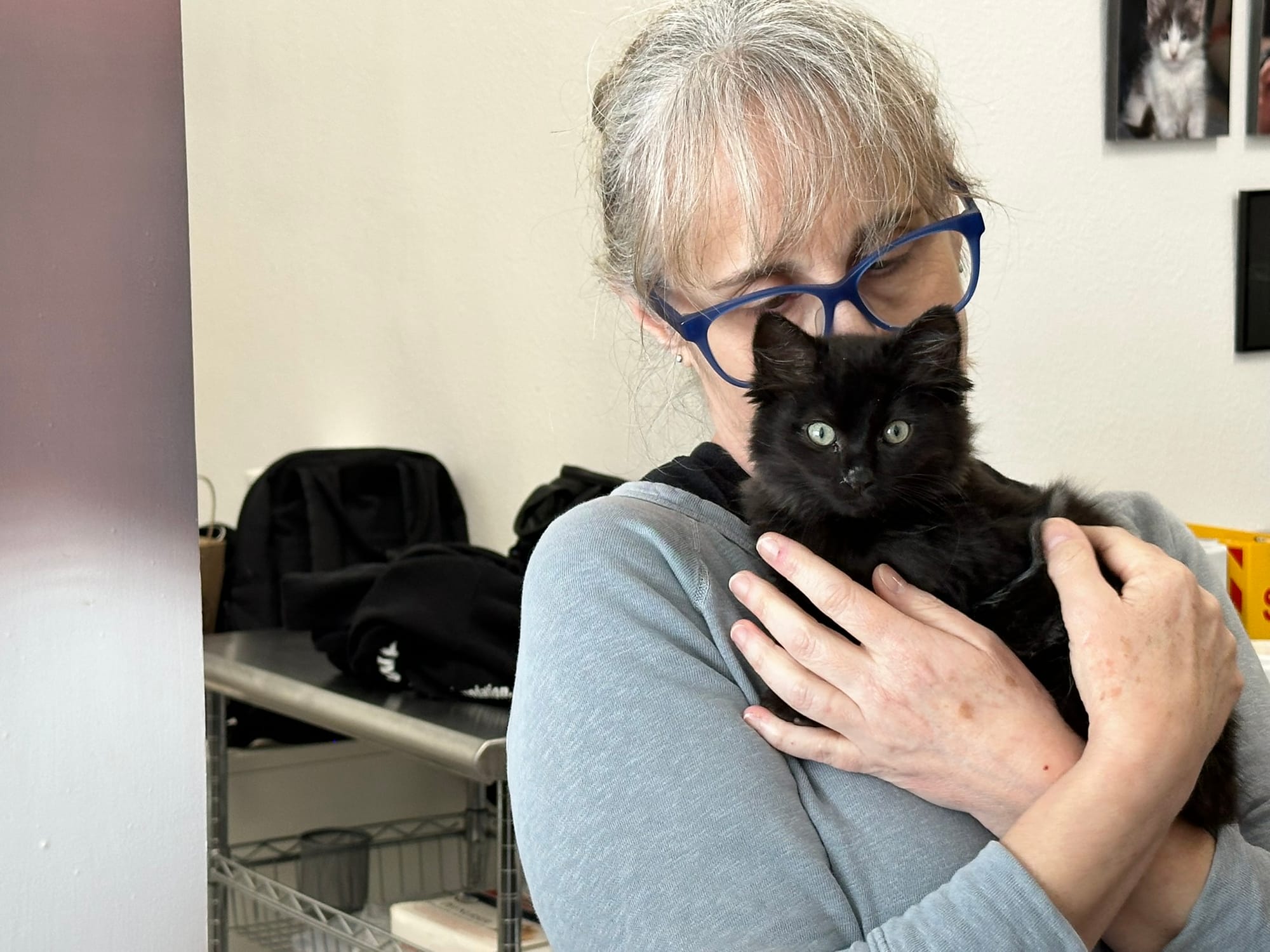 A woman cradles a black kitten.