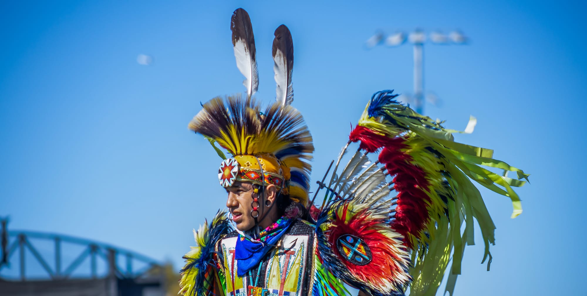 Headshot of a man outside wearing colorful Native American clothing.