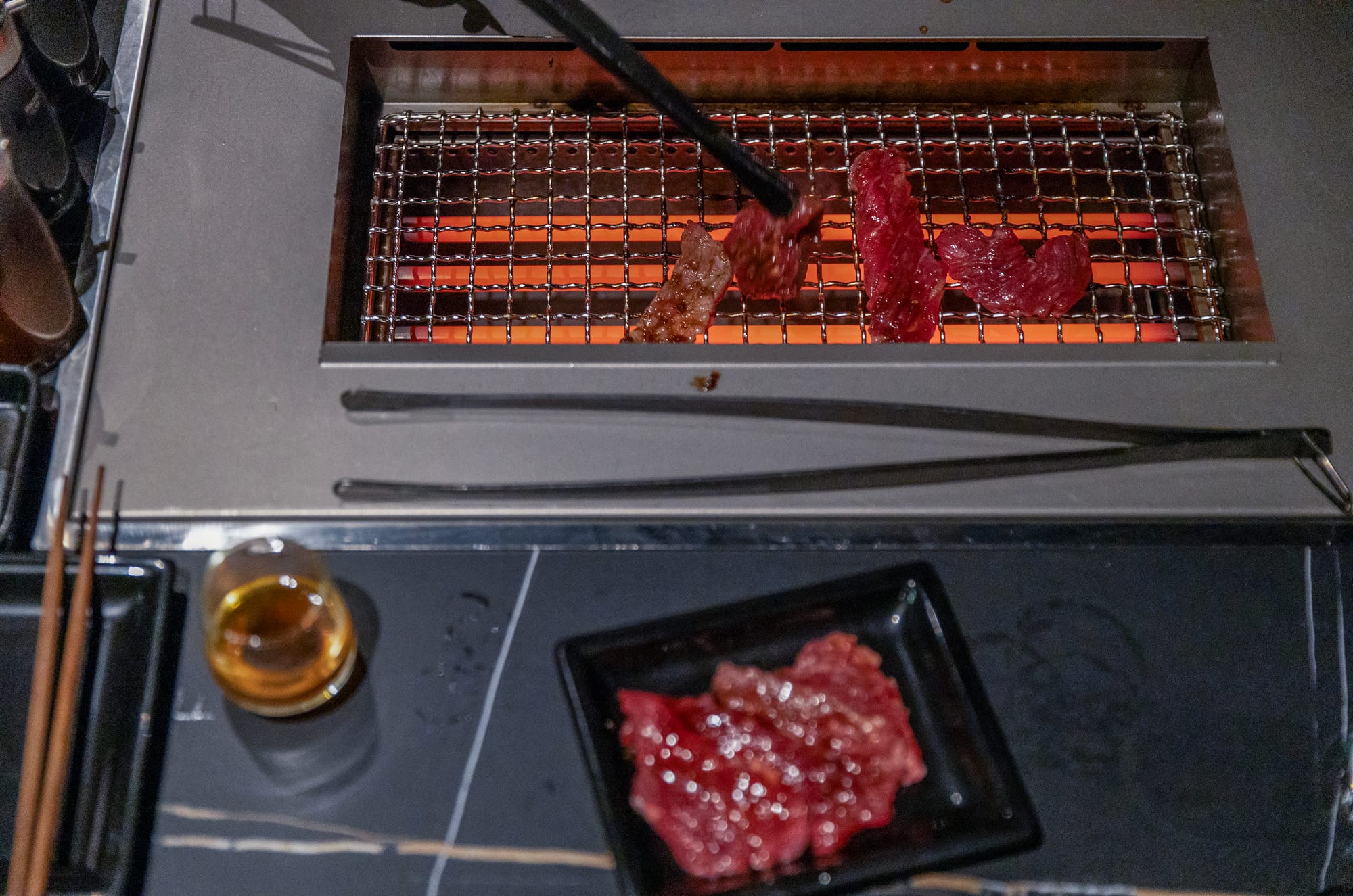 Meat cooking on a small metal grill.