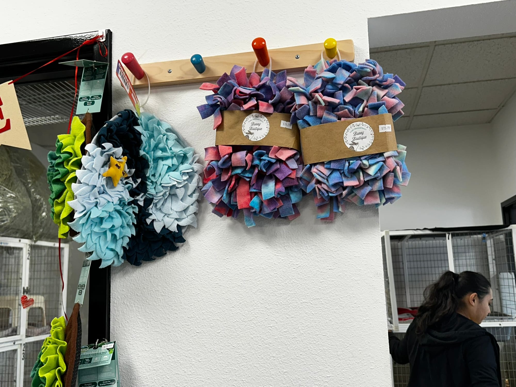 Colorful scratching mats hang on a wall next to a woman.
