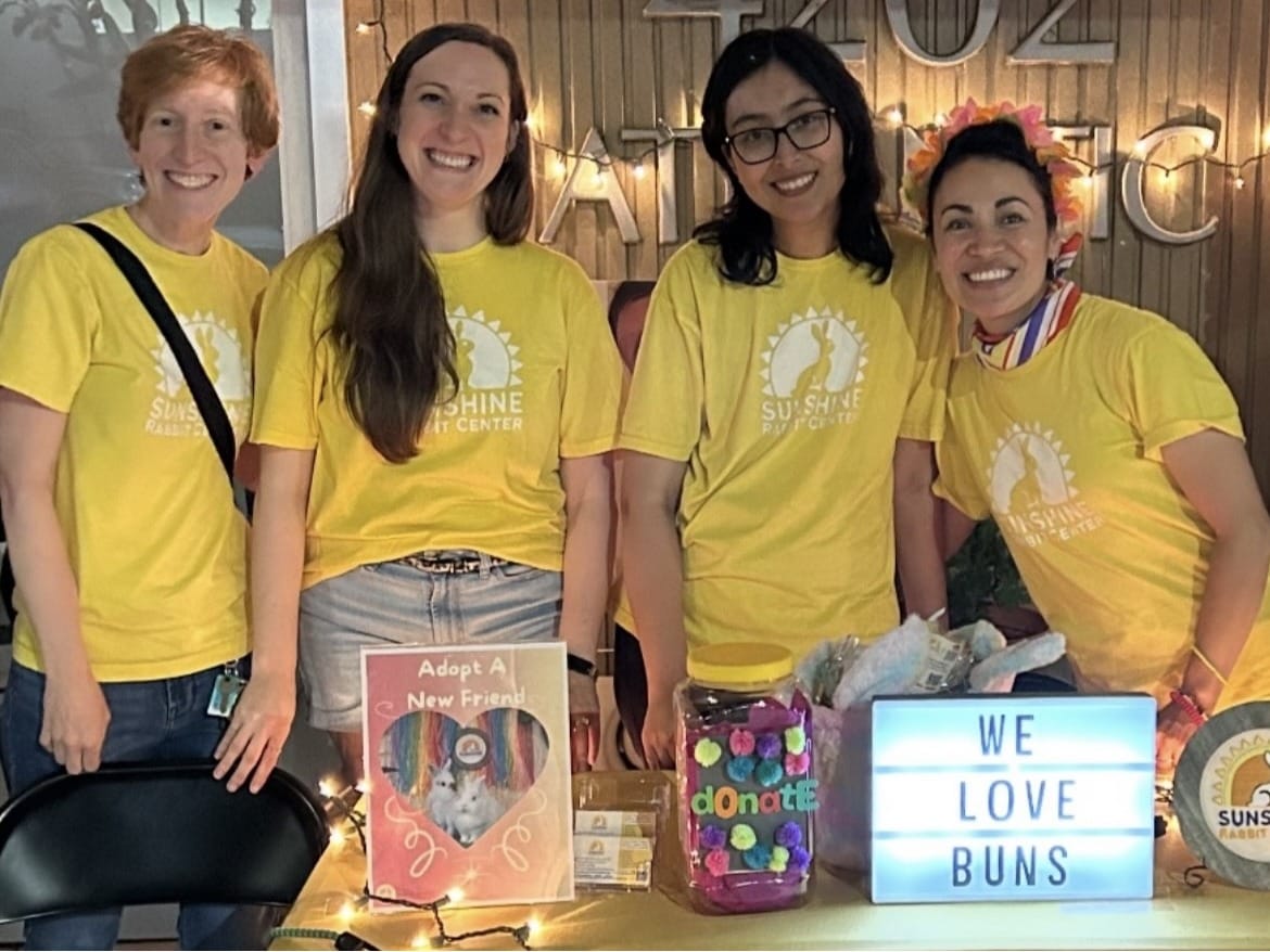 Four people wearing yellow shirts smile.