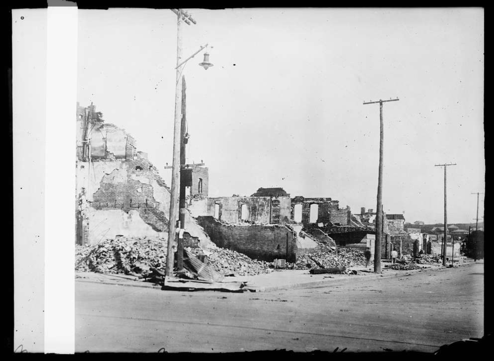 Black and white photo of an entire city block of burned out brick buildings.
