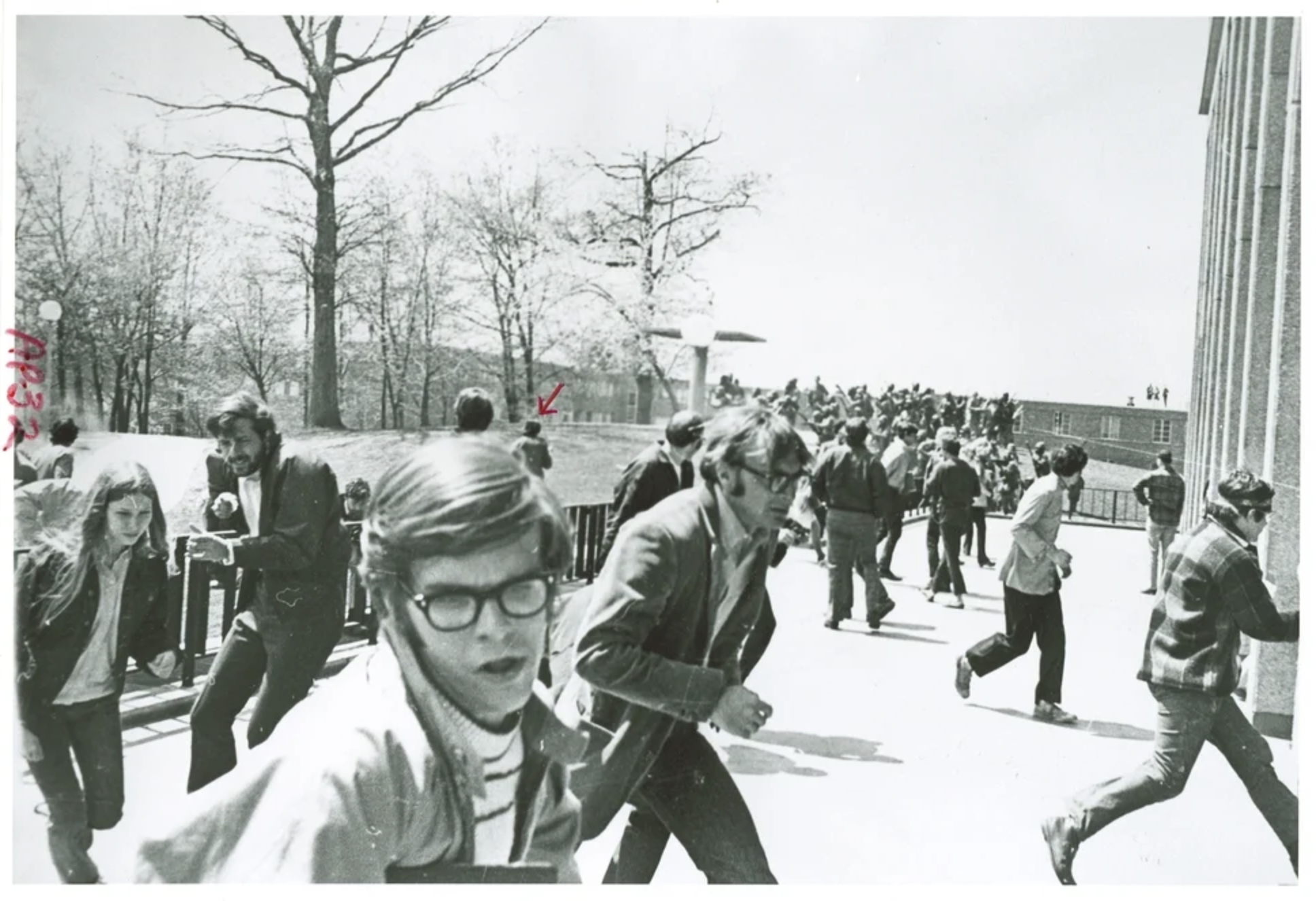 Black and white photo of a large group of people running across a college campus.
