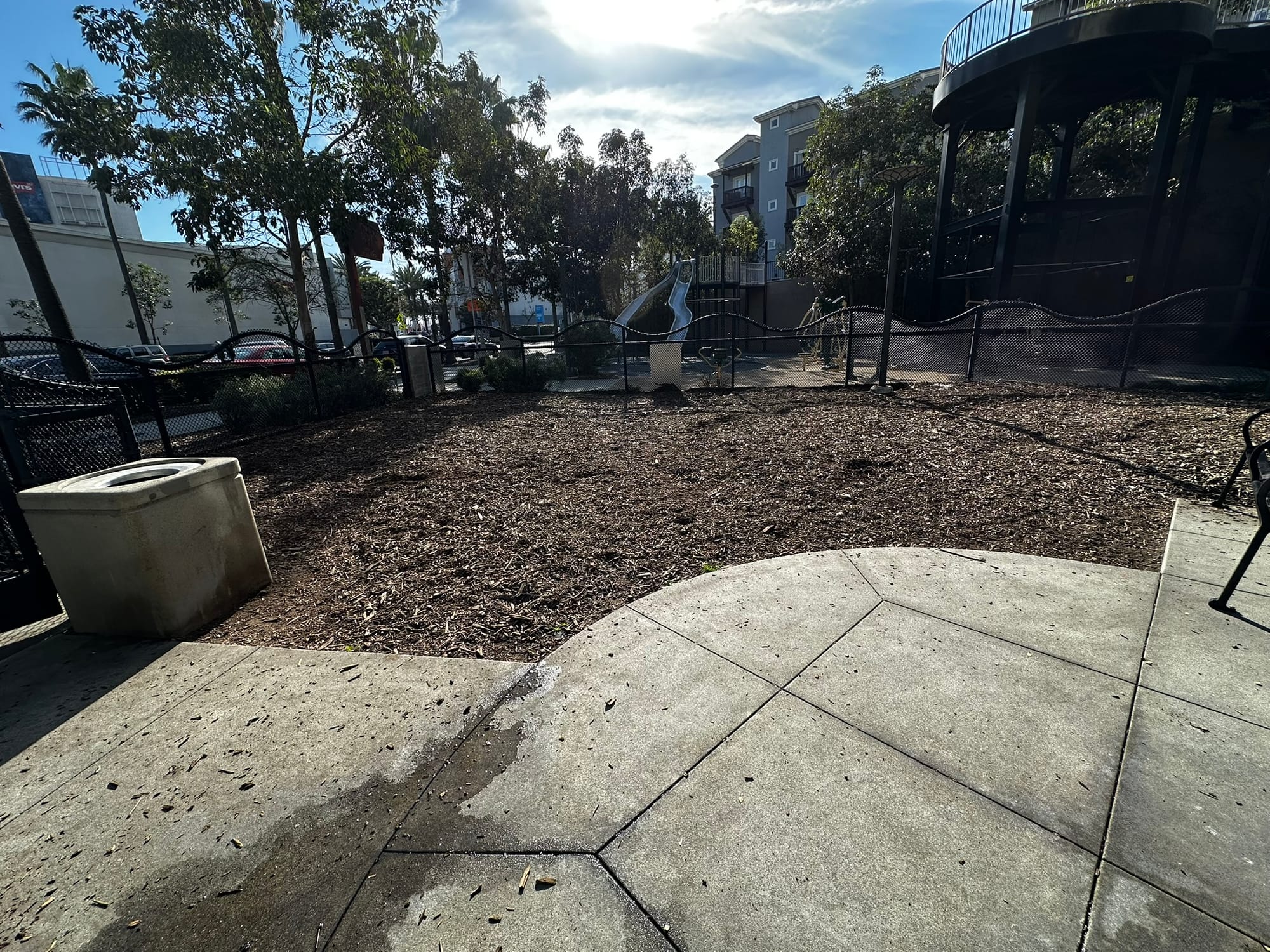 A small fenced-off park surrounded by tall buildings.