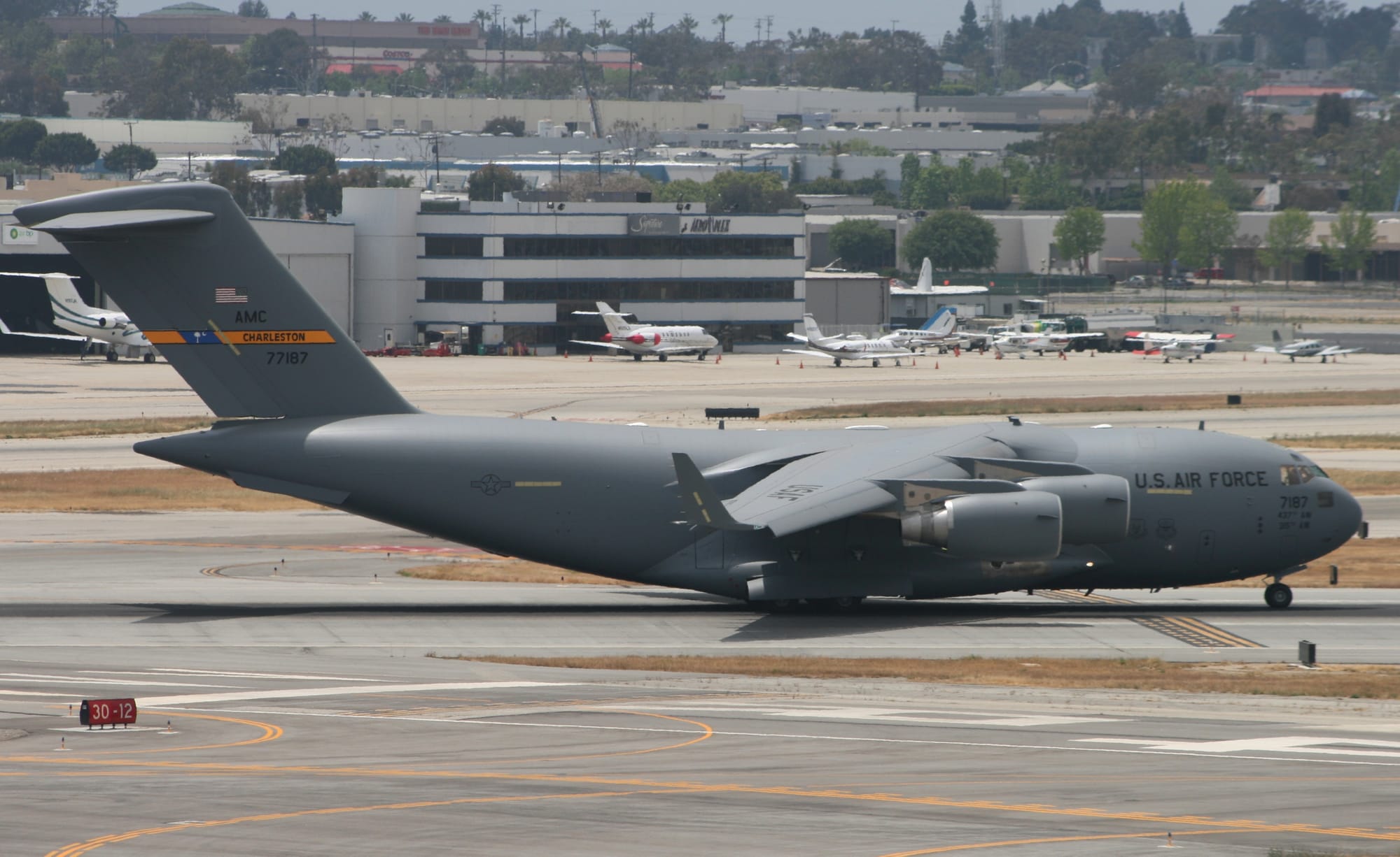 A fat gray airplane sits on the runway at an airport.
