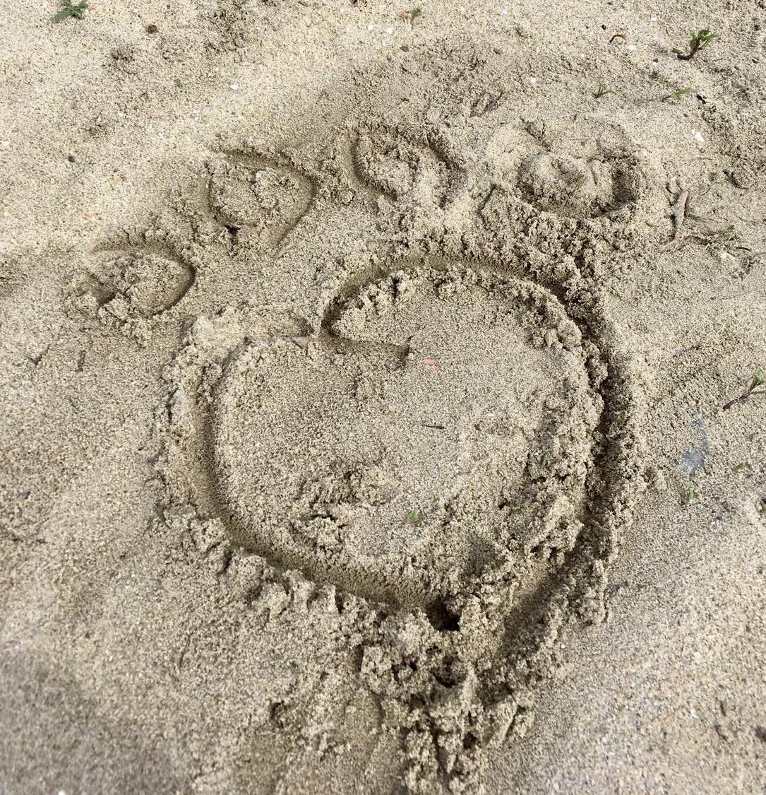 The outline of a heart on the sand at a beach.