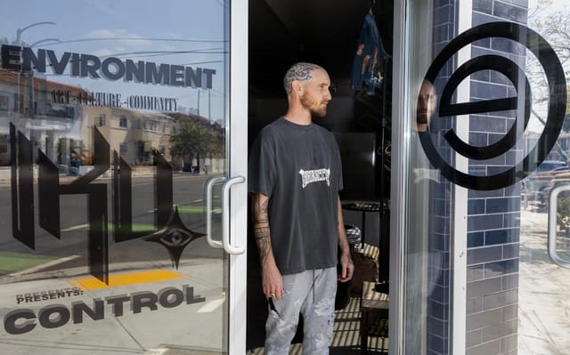 Man looks thoughtful next to a glass door that reflects his image.