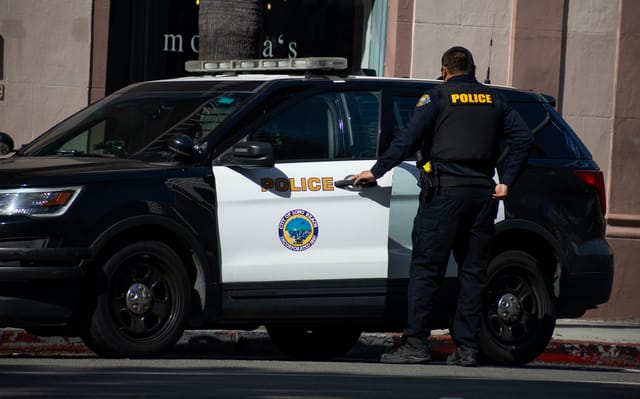 Police officer opens the door of a police car in front of a restaurant.