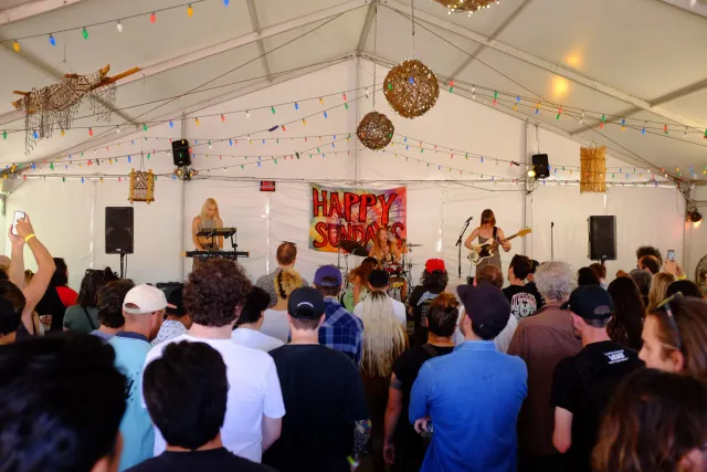 A group of people watch two people on stage playing a guitar and keyboard.