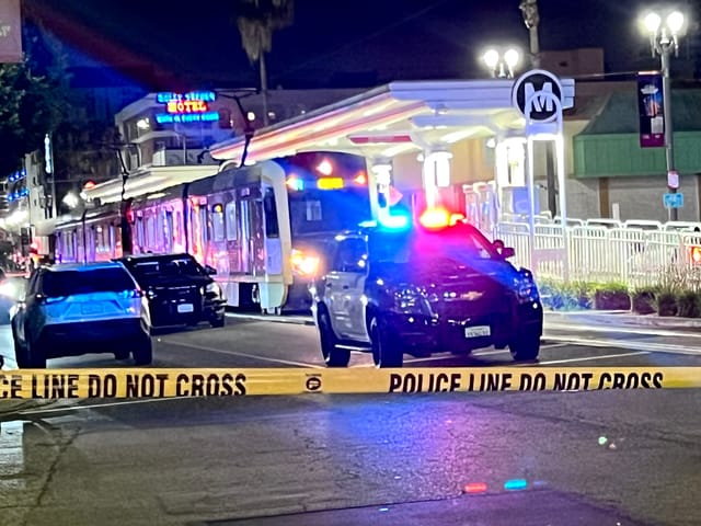 Police car on a dark street behind yellow caution tape. 