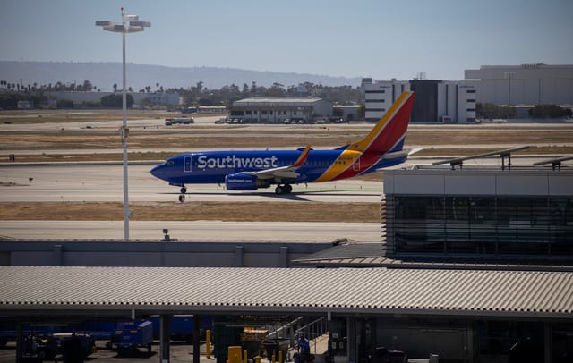 A red, yellow and blue airplane with the word "Southwest" in white on the side sits on a runway.