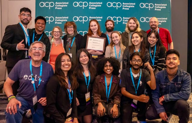 A large group of college-aged students and their teachers post for a picture at an award ceremony.