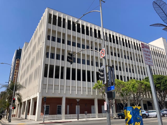 A large, multi-story building with vertical slats around the facade is seen near Downtown Long Beach.