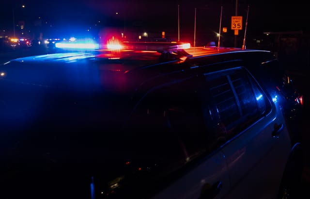 A cop car's lights flash red and blue at night.