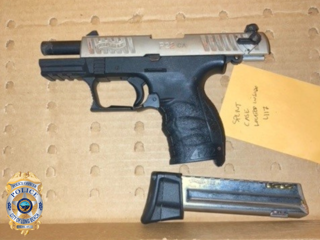 A black and gray handgun lying on a piece of cardboard next to its clip with the LBPD logo in the lower left corner.