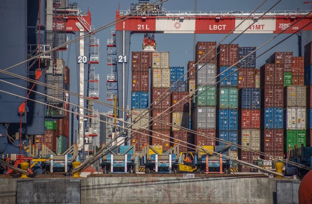 Different colored shipping containers stacked on a dock.