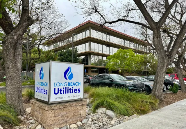 Cars parked near a glassy office building near a sign saying "Long Beach Utilities."