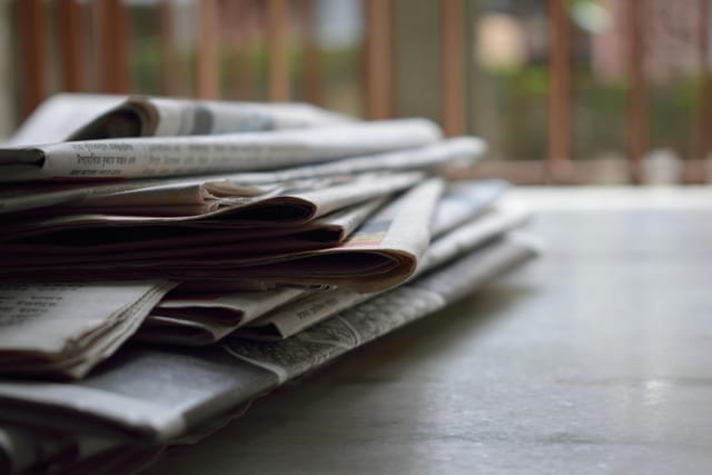 A stack of newspapers folded in half sits on a table.