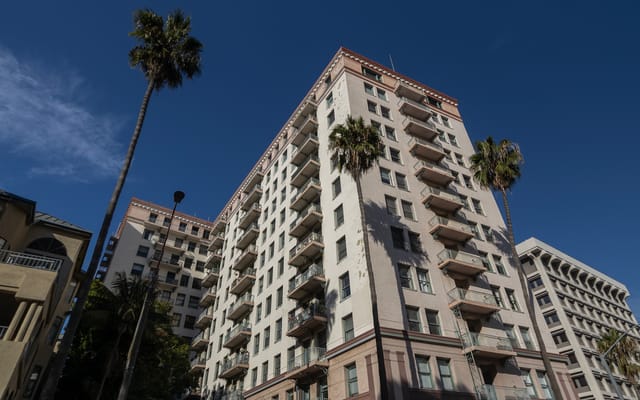 A white mid-rise building surrounded by palm trees.