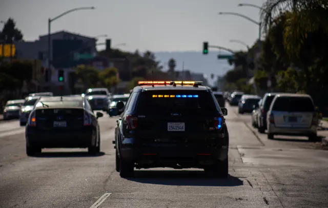 A police car drives in traffic on a busy street.